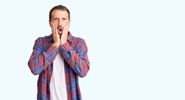 Gündelik kıyafetler giyen genç yakışıklı adam korkmuş ve şok olmuş, şaşırmış ve şaşırmış bir yüz ifadesi var. 