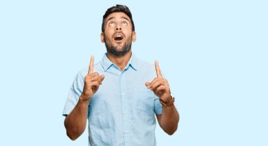 Yakışıklı, sıradan kıyafetler giyen, şaşkın şaşkın bakan, parmaklarıyla işaret eden ve kollarını kaldıran bir İspanyol.. 