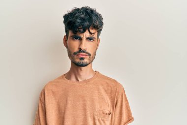 Gündelik kıyafetler giyen, kuşkucu ve gergin genç İspanyol bir adam sorun yüzünden surat asıyor. negatif kişi. 