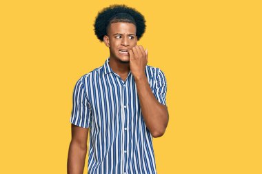 Afro saçlı, sıradan kıyafetler giyen, gergin ve elleri ağızda, tırnaklarını yiyormuş gibi görünen Afro-Amerikan bir adam. anksiyete. 