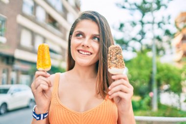 Ortadoğulu genç kız gülümsüyor, şehirde dondurma yiyor..