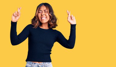 Genç, güzel, melez, sıradan kıyafetler giyen, umut ve gözlerin kapalı bir şekilde parmaklarını çapraz gösteren bir kadın. Şans ve batıl inançlar. 