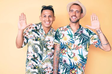 Yazlık şapkalı ve Hawaii tişörtlü iki genç gay merhaba diyor mutlu ve güler yüzlü, dostça bir jest. 