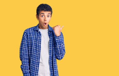 Gündelik giysiler giyen genç Afro-Amerikan bir adam elleri yandan işaret ederek şaşırdı, ağzı açık hayret içinde kaldı.. 