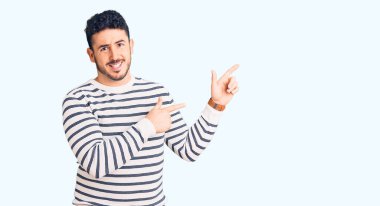 Gündelik kıyafetler giyen genç İspanyol bir adam iki eliyle endişeli ve endişeli bir ifadeye işaret ediyor. 