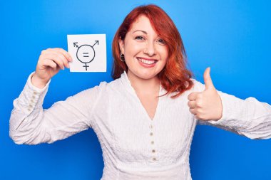 Kızıl saçlı kadın cinsiyet ayrımcılığı istiyor. Elinde transseksüel eşitlik mesajı olan bir kağıt tutuyor. Mutlu ve olumlu gülümsüyor.