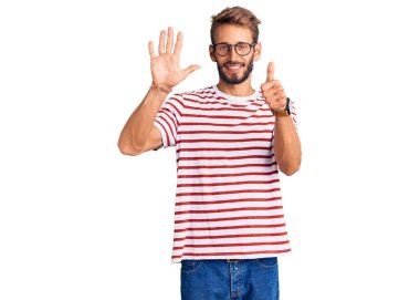 Sakallı, sıradan kıyafetler giyen ve gözlüklü yakışıklı bir adam. Altıncı parmaklarını gösterip gösterirken kendinden emin ve mutlu bir şekilde gülümsüyor.. 