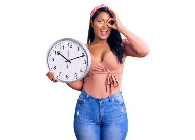 Uzun saçlı, uzun saçlı, gülümseyen, mutlu bir İspanyol kadın. El pençe divan duran parmaklarıyla işaret veriyor. 