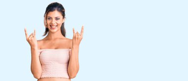 Genç ve güzel bir kadın gündelik kıyafetler giyip çılgın bir ifadeyle bağırıyor ve elleri havada rock sembolü yapıyor. Müzik yıldızı. ağır müzik konsepti. 