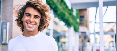 Genç, yakışıklı, gülümseyen bir İspanyol. Şehrin caddesinde mutlu bir şekilde yürüyor.