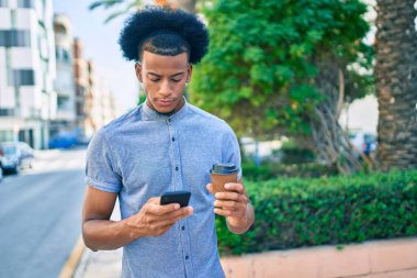 Mutsuz bir suratı olan, akıllı telefon kullanan ve şehirde kahve içen genç bir Afrikalı Amerikalı..