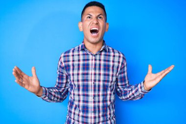 Genç, yakışıklı, gündelik kıyafetler giyen çılgın ve deli gibi bağıran, agresif ifadeli ve kollarını kaldırmış Latin bir adam. hüsran kavramı. 