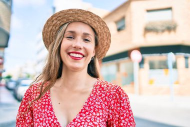 Genç sarışın kadın tatilde gülümsüyor. Mutlu bir şekilde caddede yürüyor.