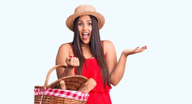 Genç, güzel esmer kadın elinde piknik sepeti olan yaz şapkalı mutlu bir gülümsemeyle zaferi kutluyor ve kazanan el kaldırarak ifade veriyor. 