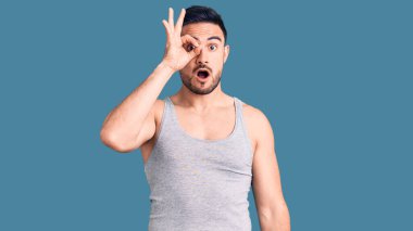 Mayo giyen ve kolsuz tişört giyen genç yakışıklı adam şaşırmış yüz ve parmaklarından bakan gözlerle şok olmuş bir jest yapıyor. İnançsız ifade. 