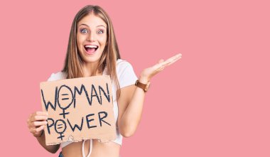 Genç, sarışın bir kadın elinde güç bayrağı, zaferi mutlu bir gülümsemeyle ve kazanan bir ifadeyle kutluyor. 