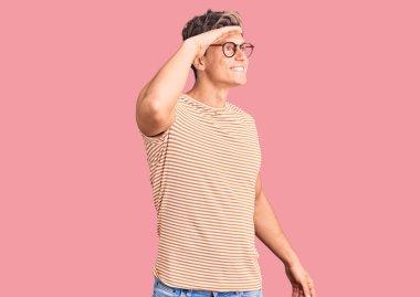 Gündelik kıyafetler ve gözlük takan genç yakışıklı adam çok mutlu ve gülümseyerek başını kaldırmış uzaklara bakıyor. arama kavramı. 