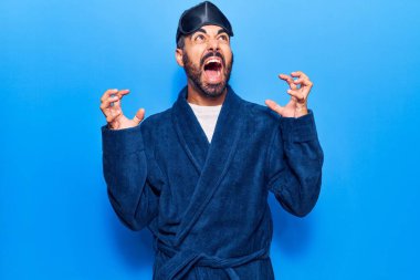 Uyku maskesi takan genç İspanyol bir adam deli gibi bağırıyor, bağırıyor, agresif bir ifade ve kollarla bağırıyor. hüsran kavramı. 