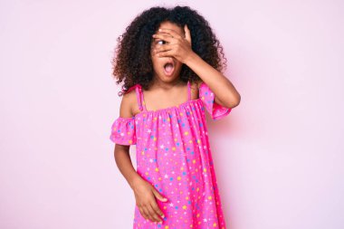 Kıvırcık saçlı Afro-Amerikan çocuğu. Şoka girmiş, yüzünü ve gözlerini kapamış, utangaç ifadesiyle parmaklarından bakıyor.. 