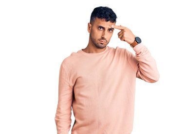 Alnındaki sivilceden mutsuz olduğunu gösteren günlük kıyafetler giyen genç İspanyol adam, siyah başlıklı çirkin enfeksiyon. sivilce ve deri problemi 