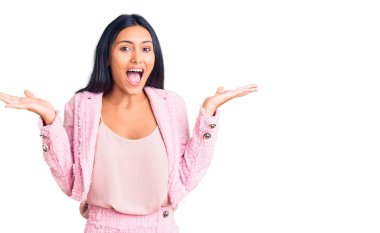 İş kıyafetleri giymiş genç ve güzel bir Latin kız çılgın ve başarıyı kollarını kaldırıp heyecanla haykırarak kutluyor. Kazanan konsept 