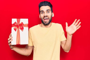 Sakallı, genç ve yakışıklı bir adam başarıyı mutlu bir gülümsemeyle ve kazanan bir ifadeyle kutluyor. 