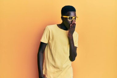 Gündelik kıyafetler ve gözlük takan genç Afro-Amerikan adam ağzıyla ağzını kapatmaktan sıkıldı. Huzursuz ve uykulu.. 