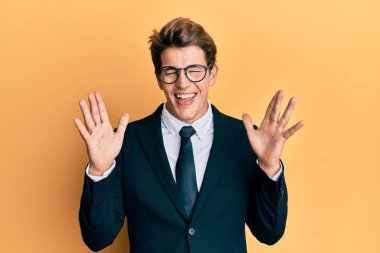 İş elbisesi giymiş, kravatlı yakışıklı, çılgın ve çılgın başarısını kutlayan, kollarını kaldırmış ve gözleri kapalı heyecanlı bir beyaz adam. Kazanan konsept 