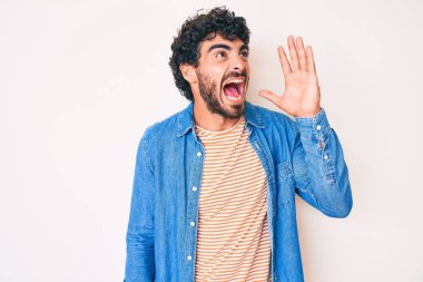 Kıvırcık saçlı, ayılı, sıradan bir kot ceket giyen, el ele tutuşup bağıran yakışıklı bir genç. iletişim konsepti. 