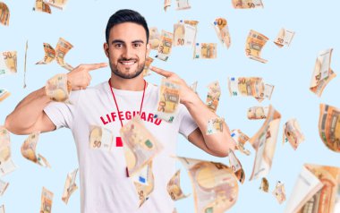 Cankurtaran üniforması giyen, neşeli gülümseyen, parmakları, dişleri ve ağzıyla işaret eden genç yakışıklı bir adam. diş sağlığı kavramı.