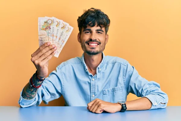 Joven Hombre Hispano Sosteniendo Reino Unido Billetes Libras Sentados Mesa —  Fotos de Stock