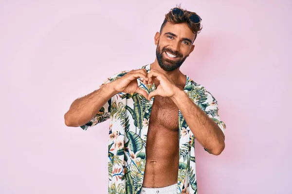 Young hispanic man wearing casual summer clothes smiling happy doing ok sign with hand on eye looking through fingers