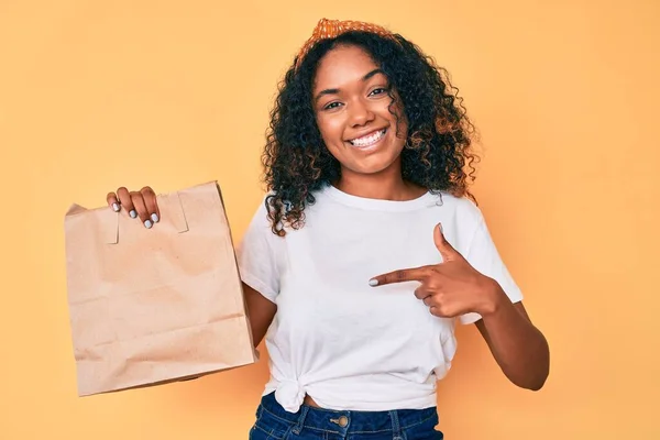 Jovem Afro Americana Segurando Tirar Saco Papel Sorrindo Feliz Apontando — Fotografia de Stock