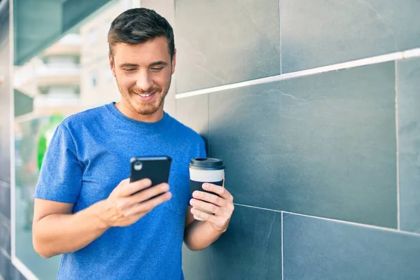 若い白人男性がスマートフォンを使って街でコーヒーを飲んでいます — ストック写真