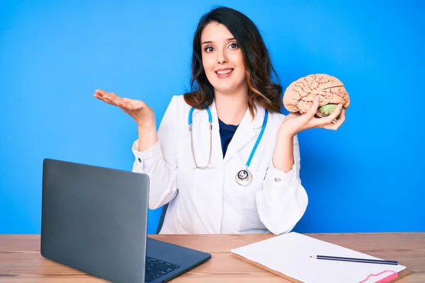 Joven Hermosa Morena Con Abrigo Médico Sosteniendo Cerebro Oficina Celebrando — Foto de Stock