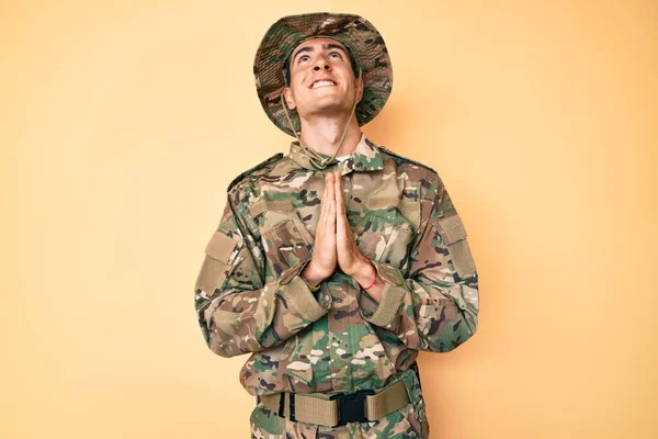 カモフラージュ軍の制服を着た若いハンサムな男が物乞いをし 顔に希望の表現と一緒に手で祈る非常に感情的かつ心配しました お願い — ストック写真
