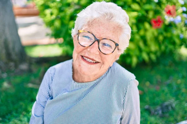 Elder senior woman with grey hair smiling happy outdoors at the park