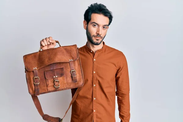 Junger Hispanischer Mann Mit Ledertasche Und Nüchternem Gesichtsausdruck Der Selbstbewusst — Stockfoto