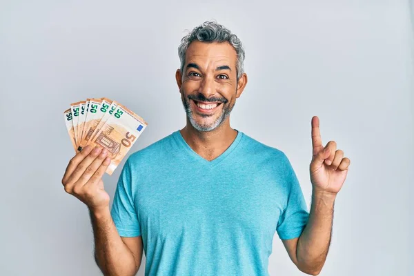 Orta Yaşlı Gri Saçlı Elinde Euro Banknotla Gülümseyen Bir Adam — Stok fotoğraf