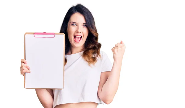 Mulher Morena Bonita Segurando Prancheta Com Espaço Branco Gritando Orgulhoso — Fotografia de Stock