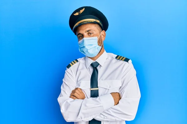 髭を生やしたハンサムな男は 飛行機のパイロットの制服を着て安全マスク懐疑的で緊張し 両腕を組んで顔に不承認の表現を身に着けている 否定的な人 — ストック写真