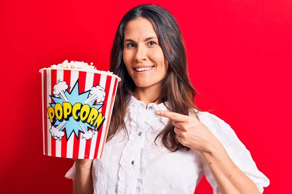 Giovane Bella Donna Bruna Mangiare Pacchetto Popcorn Sfondo Rosso Isolato — Foto Stock