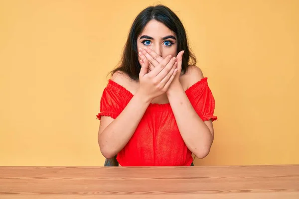 Morena Adolescente Con Ropa Casual Sentada Mesa Impactada Cubriendo Boca —  Fotos de Stock