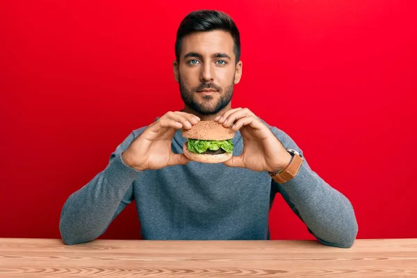 Hombre Hispano Guapo Comiendo Una Sabrosa Hamburguesa Clásica Relajado Con — Foto de Stock