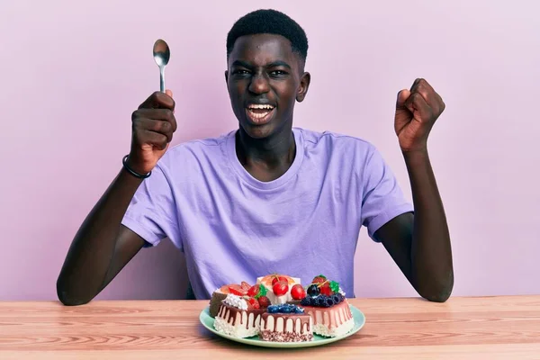 Jeune Homme Afro Américain Assis Sur Table Mangeant Des Gâteaux — Photo