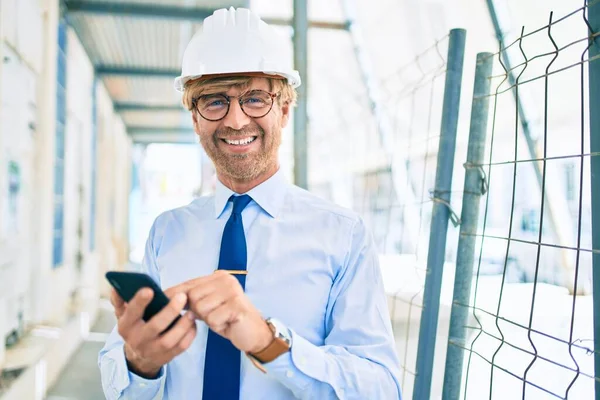 商务建筑师 头戴硬礼帽 站在建筑项目的室外 用智能手机 — 图库照片