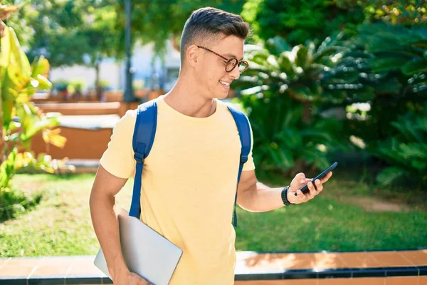 Молодой Латиноамериканец Улыбается Счастливо Используя Смартфон Гуляя Университетскому Кампусу — стоковое фото