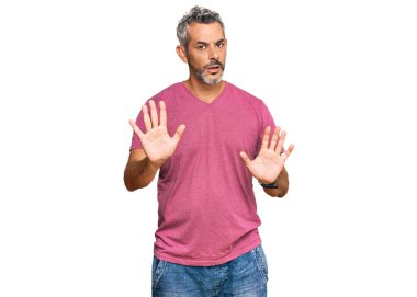 Orta yaşlı, gri saçlı, günlük kıyafetler giyen, avuç içlerini hareket ettiren, reddeden korkmuş ve iğrenç bir ifadeyle reddeden bir adam. Dur ve yasakla. 