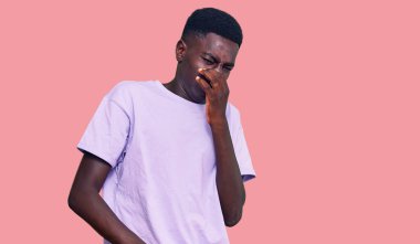 Genç, Afro-Amerikan bir adam günlük giysiler giymiş pis ve iğrenç bir koku alıyor, dayanılmaz bir koku, parmakları burnunda nefesini tutuyor. Kötü kokuyor. 