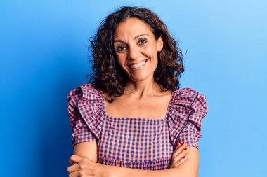 Orta yaşlı, güzel, sıradan tişört giyen mutlu yüzlü, kollarını kavuşturup kameraya bakan bir kadın. pozitif kişi. 